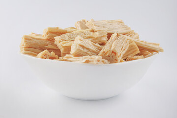 Fuzhu soy sticks in a white plate on a white background. Yuba. Side view.