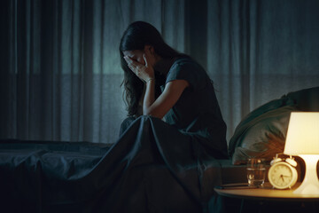Sad young woman awake in bed at night