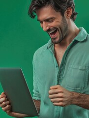 Smiling man in blue and white striped shirt, holding tablet, against green background.