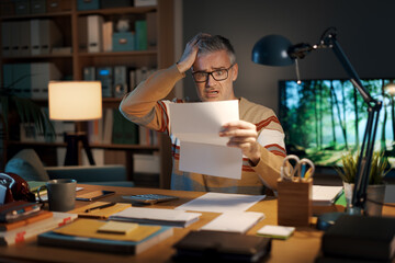Stressed man checking an expensive invoice