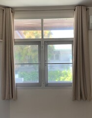 white window with curtain, Empty beige wall room in sunlight from window, blowing white sheer, brown blackout curtain,