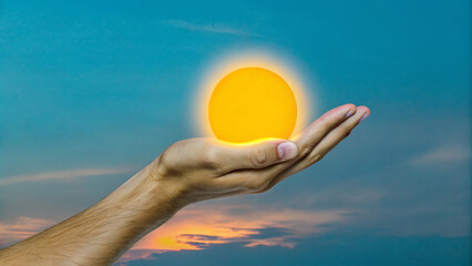 Close-up of a hand cupping a glowing sun at sunset