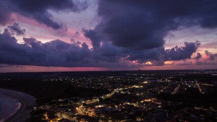Aerial view of coastal city at dusk with dramatic clouds.
