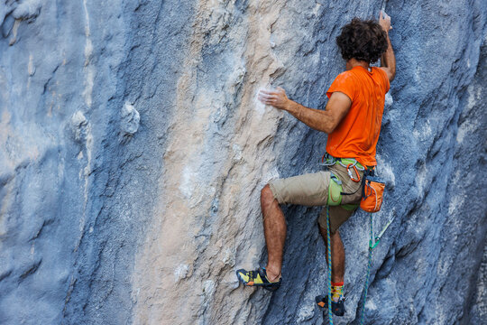 rock climber climbs on a rock. A strong man climbs a rock. Strong muscles. Endurance and strength training, man doing extreme sports. - Powered by Adobe