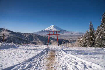 Red Japanese Torii pole, Fuji mountain and snow in Kawaguchiko, Japan. Forest trees nature landscape background in winter season.