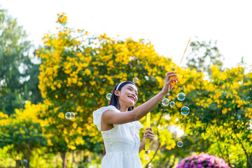 Fototapeta premium Asian Woman Blowing Bubbles in a Park
