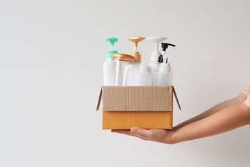 Woman hand holding box of plastic bottles and jar for refill liquid soap, shampoo and other...