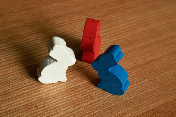 White, red and blue rabbits face to face on a brown wooden table using macro photography