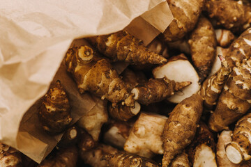 Group of fresh jerusalem artichokes in a paper bag. Jerusalem artichokes or sunroot or sunchoke. Vegetarian food. Close-up