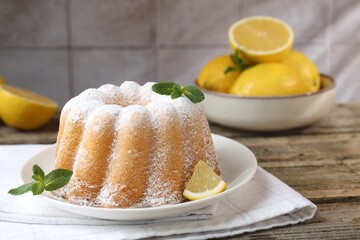 Tasty lemon cake with powdered sugar, fresh fruit slice and mint on wooden table, closeup