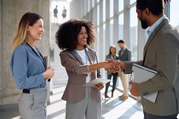 Happy business people greeting while meeting on conference in convention center.