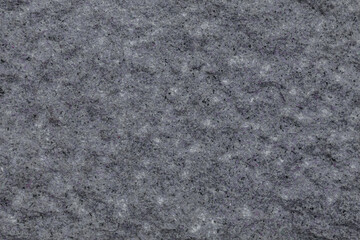 Gray granite surface with a lot of texture. The surface is not smooth. There are many small irregularities on the surface.
