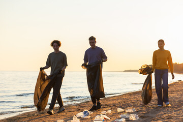 Earth day. Volunteers activists team collects garbage cleaning of beach coastal zone. Woman mans...