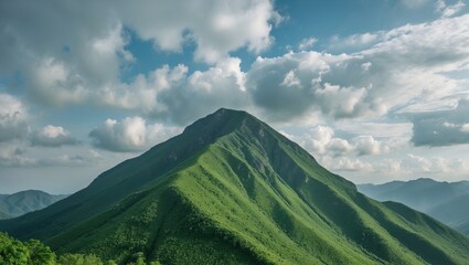 Vibrant green mountain peak under a cloudy sky in natural landscape with panoramic view Copy Space