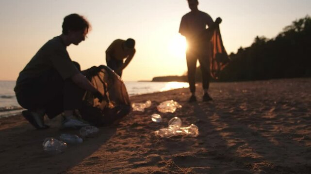 Earth day. Volunteers activists collects garbage cleaning of beach coastal zone. Woman and mans puts plastic trash in garbage bag on ocean shore. Environmental conservation coastal zone cleaning