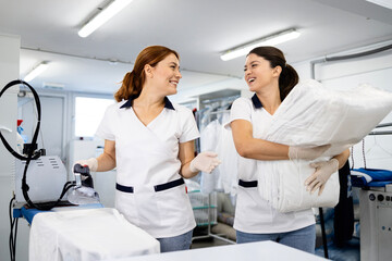 Dry cleaner workers ironing and folding clean laundry.