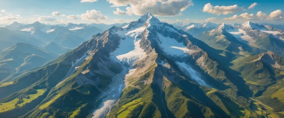 Aerial view of majestic snow-capped mountains with lush green valleys and dramatic cloud formations in a bright blue sky Copy Space