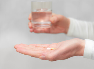 Person preparing to take medication with a glass of water in a well-lit indoor setting