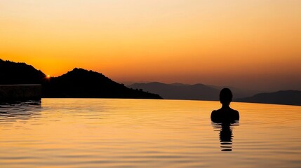 Backlit figure in tranquil water, intense orange horizon glow, dark mountain range silhouette, peaceful water surface, ambient dusk lighting, moody evening photography, minimal composition
