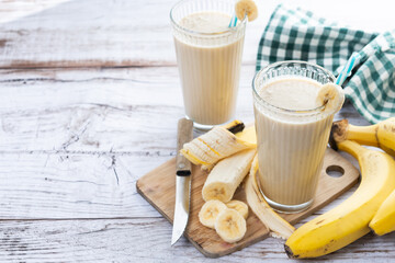 Fresh banana smoothie on white wooden table. Copy space