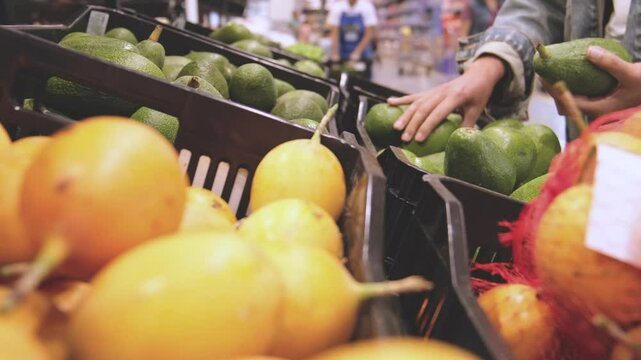 Young Woman Choosing Avocados in Grocery Store. Concept of healthy food, bio, vegetarian, diet. Selective focus