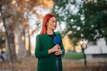 Female reporter holding microphone, broadcasting live news outdoors