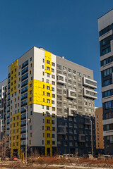Fototapeta premium Modern apartment buildings with yellow and gray facades against a clear sky