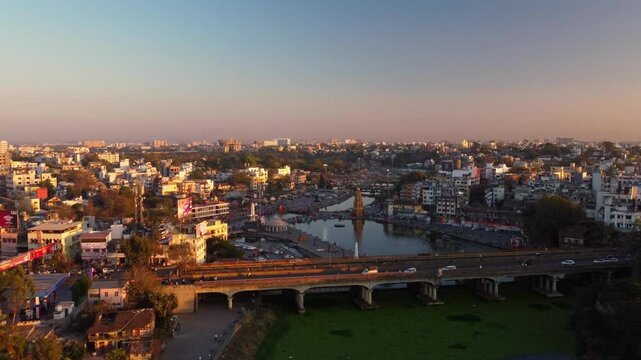 Drone view of Nashik city with Hindu pilgrimage temples and Panchavati ganga ghat on the banks of holy river Godavari in evening sunset, 2027 Kumbh Mela preparation, Establishing shot