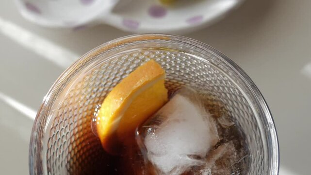 A glass of vermouth with ice cubes and a slice of orange, paired with tapas