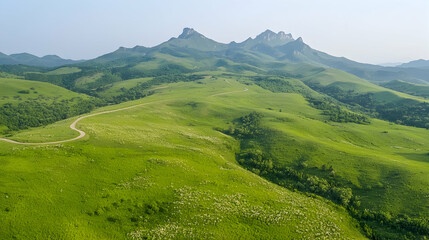 Obraz premium Winding road through green hills, mountain range backdrop, aerial view, travel landscape