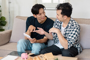 LGBTQ couple enthusiastically discussing savings plans while using a tablet in their cozy living...