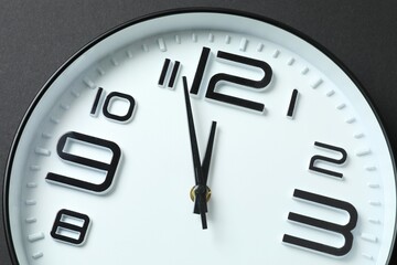 Big beautiful stylish clock showing five to twelve on black background 