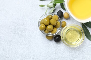 Bowl of fresh olive oil and olives with leaves on the table