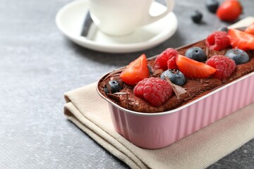 Delicious tiramisu cake with berries on table