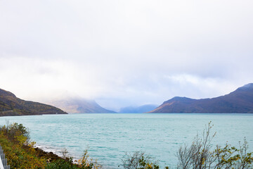 Autumn landscape of the Lyngen Alps in Northern Norway with snowy peaks, dramatic clouds, and a tranquil fjord.