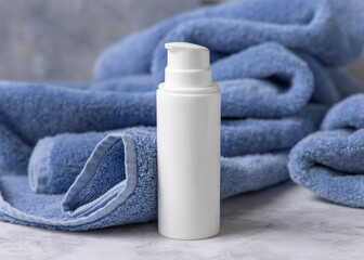 White blank one pump bottle near blue bath towel closeup, mockup. Natural handmade cosmetic