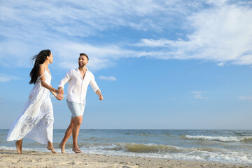 Happy young couple running together on beach
