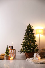 Decorated Christmas trees and other decor near light wall indoors. Festive interior design