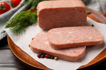 Pieces of tasty canned meat and peppercorns on wooden table, closeup