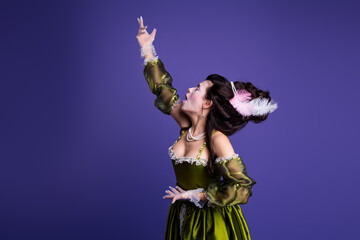 Elegant woman in luxurious green dress with retro style against purple backdrop