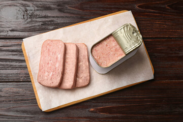 Canned meat in tin can on wooden table, top view