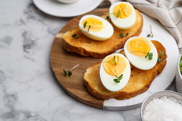 Sandwiches with hard boiled eggs on white marble table, closeup