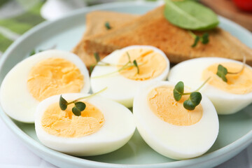 Cut hard boiled eggs with bread on white tiled table, closeup