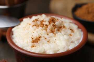 Tasty rice pudding with cinnamon on table, closeup