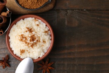 Tasty rice pudding with cinnamon served on wooden table, flat lay. Space for text