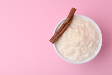 Tasty rice pudding with cinnamon on pink background, top view. Space for text