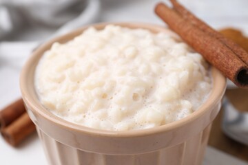 Tasty rice pudding with cinnamon on table, closeup