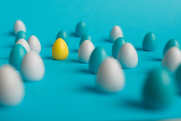 small colorful easter eggs on blue background with a focus on yellow egg