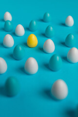 small colorful easter eggs on blue background with a focus on yellow egg
