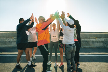 Group of runners cheering and supporting each other outdoors